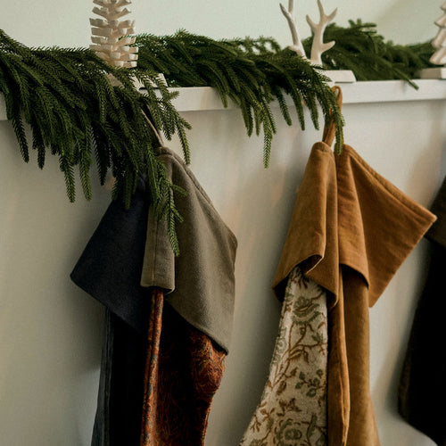 Stockings and tree skirts hanging on a mantel with greenery