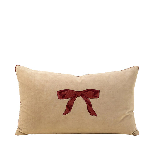 Beige pillow with a red bow design on a beige background