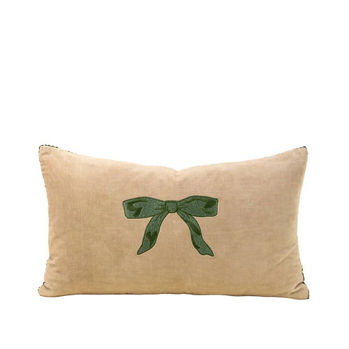 Beige pillow with a green bow design on a beige background
