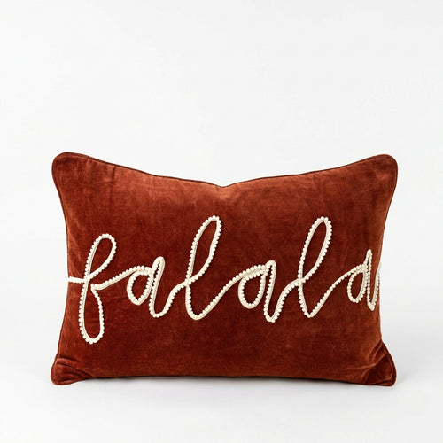 Brown pillow with 'falalal' embroidery on a beige background