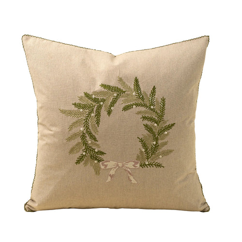 Decorative pillow with embroidered greenery and ribbon design on a beige background