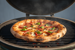 Pizza being cooked on a grill with smoke rising