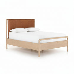 Bed with brown leather headboard and white bedding on a white background